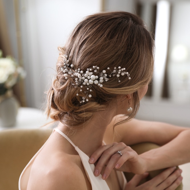 Coiffure de Mariage : Chignon Bas avec Bijou de Tête Coiffure de mariée avec un chignon bas élégant orné d'un peigne en perles et cristaux scintillants.